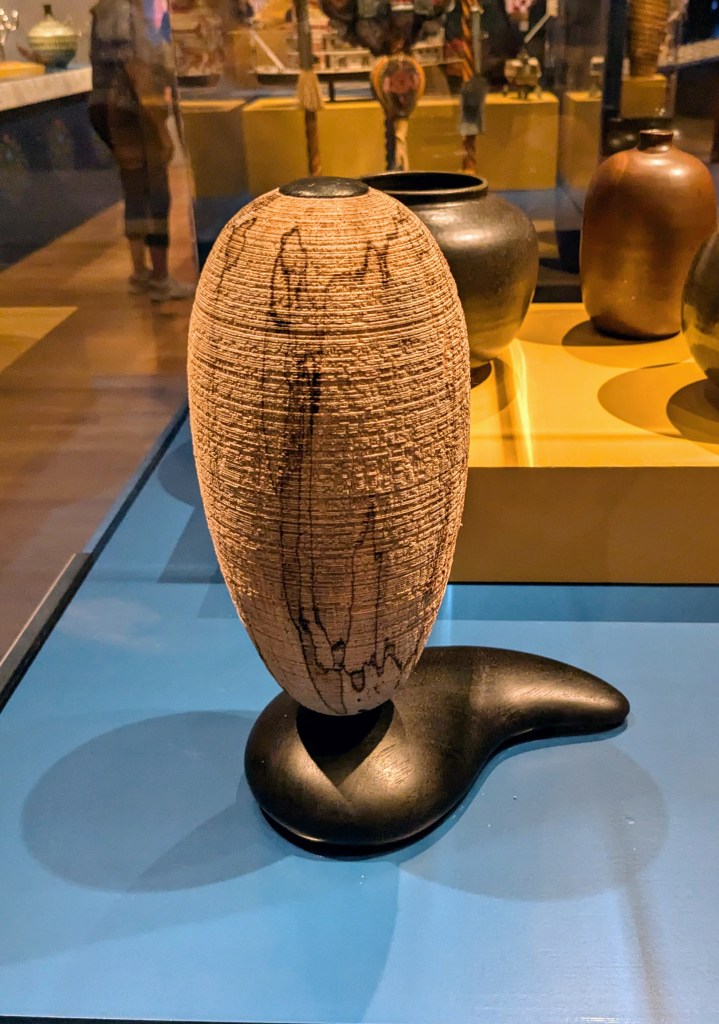 A vase-shaped wooden object on display.